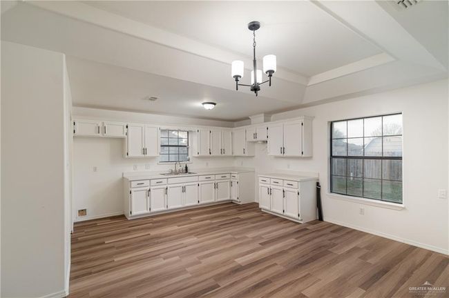 Kitchen featuring light wood finished floors, white cabinetry, and a sink | Image 5