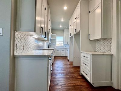 Kitchen featuring backsplash, dark hardwood / wood-style flooring, and white cabinets | Image 3