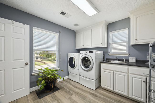Spacious laundry room with ample cabinets, a convenient sink, and a walk-in pantry. Perfectly situated next to the kitchen. | Image 21