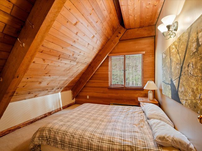Carpeted bedroom featuring vaulted ceiling with beams, wood walls, wood ceiling, and baseboards | Image 27