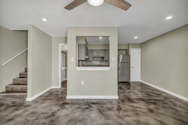 Unfurnished living room with concrete floors, baseboards, ceiling fan, stairs, and recessed lighting | Image 21