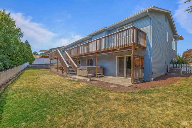 Rear view of house featuring a hot tub, a wooden deck, a fenced backyard, and a patio area | Image 42