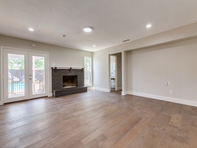 Unfurnished living room featuring french doors, wood finished floors, baseboards, a fireplace, and recessed lighting | Image 4