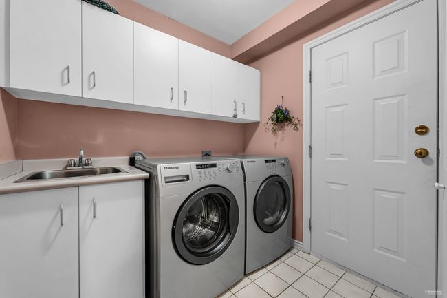 Laundry room with light tile patterned flooring, washer and clothes dryer, a sink, and cabinet space | Image 21