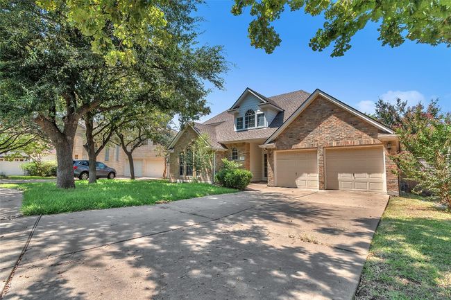 Traditional home featuring a shingled roof, a garage, concrete driveway, brick siding, and a front lawn | Image 26