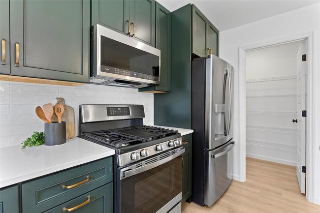 Kitchen with light hardwood / wood-style floors, stainless steel appliances, green cabinets, and decorative backsplash | Image 32