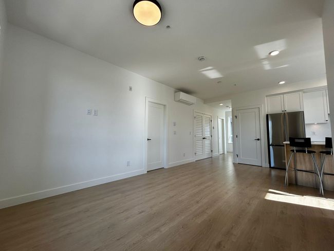 Unfurnished living room featuring recessed lighting, a wall mounted AC, wood finished floors, and baseboards | Image 7