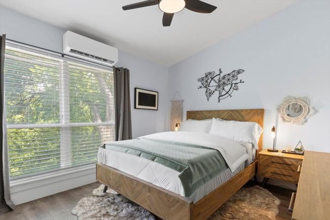 Bedroom featuring an AC wall unit, multiple windows, wood finished floors, and a ceiling fan | Image 14