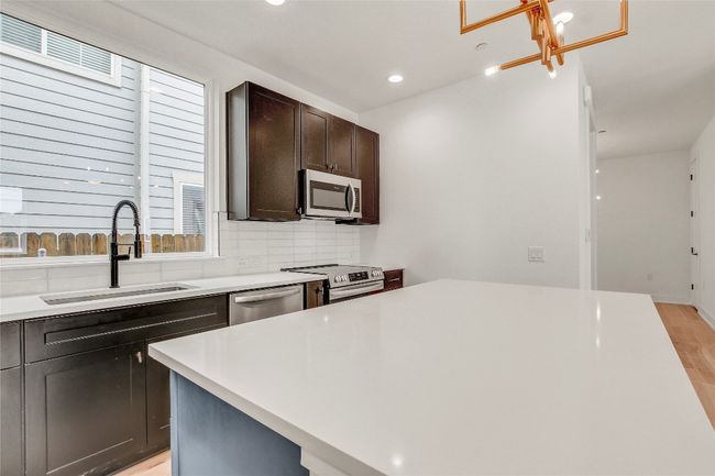 Kitchen featuring appliances with stainless steel finishes, a sink, light wood-style flooring, dark brown cabinetry, and light countertops | Image 17