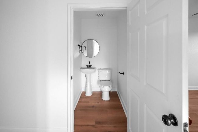 Bathroom featuring toilet, baseboards, visible vents, and wood finished floors | Image 10