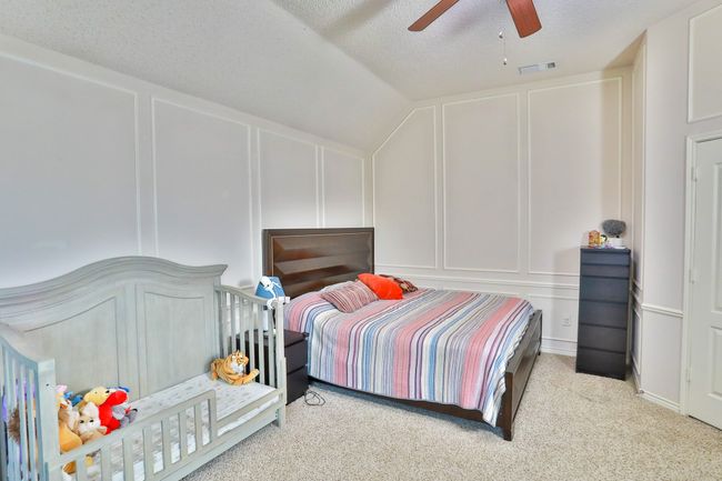 Bedroom with a decorative wall, carpet flooring, ceiling fan, lofted ceiling, and a textured ceiling | Image 17