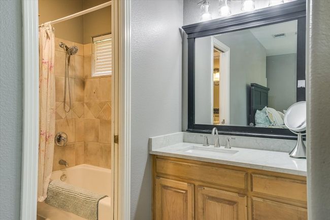 Bathroom featuring shower / bath combination with curtain, vanity, and a textured wall | Image 22