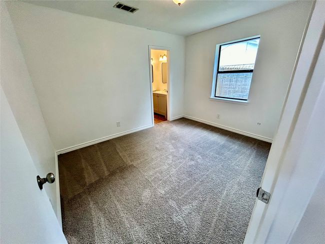 Unfurnished bedroom with dark colored carpet, ensuite bath, and baseboards | Image 19