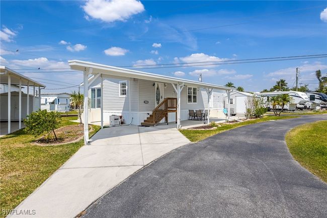 Manufactured / mobile home with aphalt driveway, a carport, a residential view, cooling unit, and a front yard | Image 5