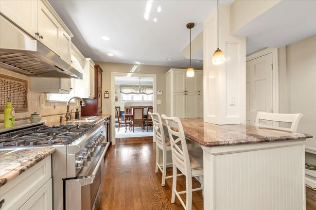 Kitchen featuring under cabinet range hood, range with two ovens, dark wood-style flooring, and a sink | Image 7