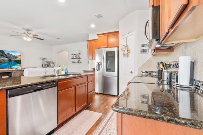 Kitchen featuring appliances with stainless steel finishes, a ceiling fan, a sink, dark stone counters, and backsplash | Image 18