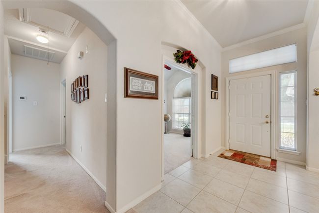 Entryway with ornamental molding, arched walkways, light colored carpet, light tile patterned flooring, and baseboards | Image 8