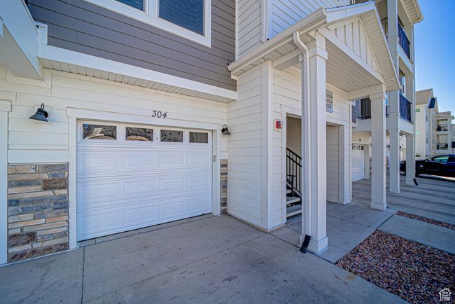 View of side of home with an attached garage, stone siding, and concrete driveway | Image 19
