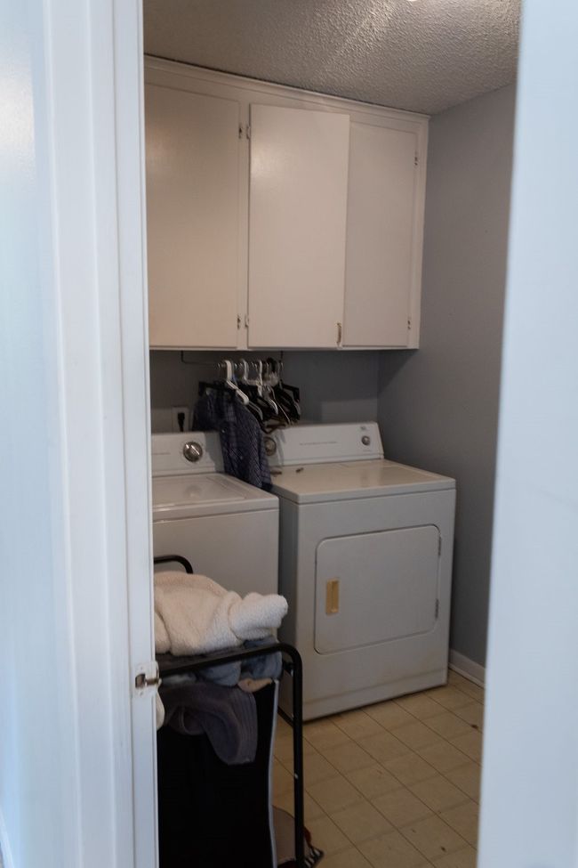 Washroom featuring washer and clothes dryer, cabinet space, a textured ceiling, and light tile patterned flooring | Image 21