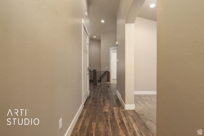 Hallway with dark wood-type flooring, an upstairs landing, recessed lighting, and arched walkways | Image 5