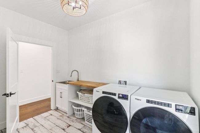 Washroom featuring washing machine and dryer, cabinet space, and a chandelier | Image 30