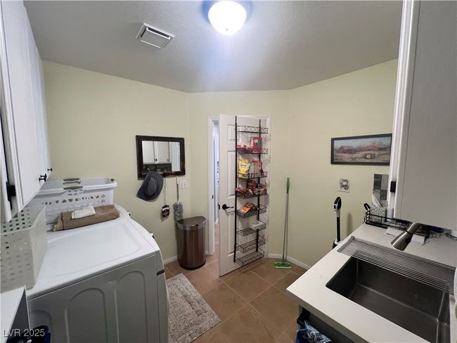 Laundry room featuring cabinet space, tile patterned floors, and washing machine and dryer | Image 24