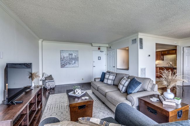 The living room boasts generous space that can easily accommodate a desk, extra seating, a piano, bookshelves, & more to suit your lifestyle. Additionally, the property includes the sofa, chair, rug, TV stand, television, coffee table, and end table. | Image 4