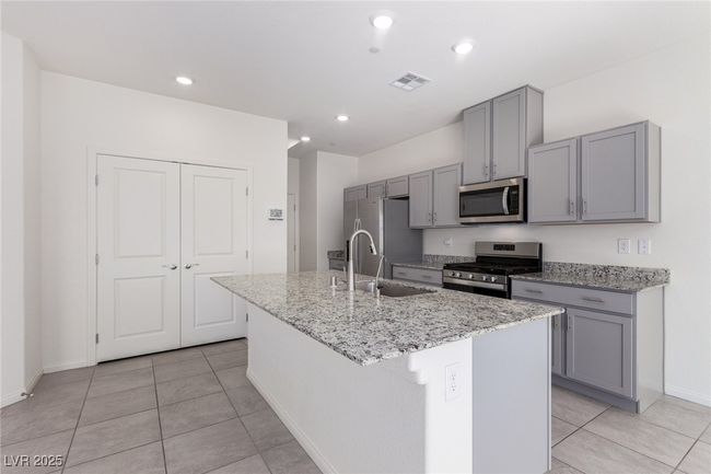 Kitchen with gray cabinetry, visible vents, a center island with sink, appliances with stainless steel finishes, and a sink | Image 7