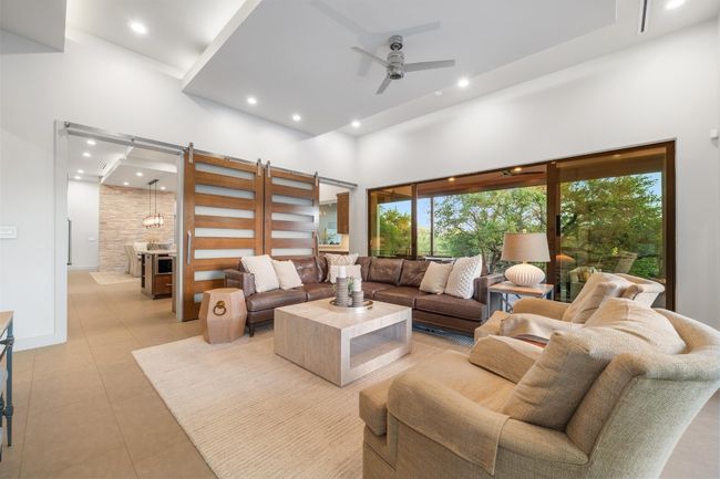 Living area featuring light tile patterned floors, ceiling fan, a wealth of natural light, and a towering ceiling | Image 13