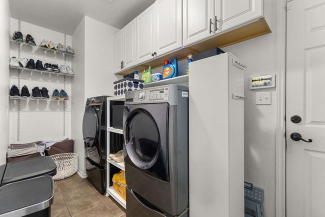 Washroom with cabinet space, light tile patterned floors, and washer and dryer | Image 34