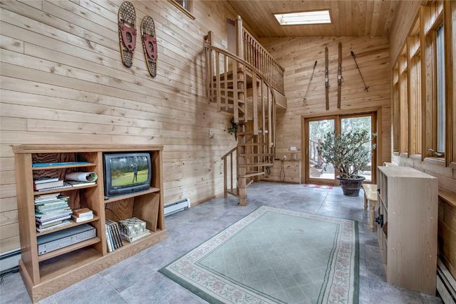 Entrance foyer featuring wood walls, baseboard heating, high vaulted ceiling, wooden ceiling, and a skylight | Image 23