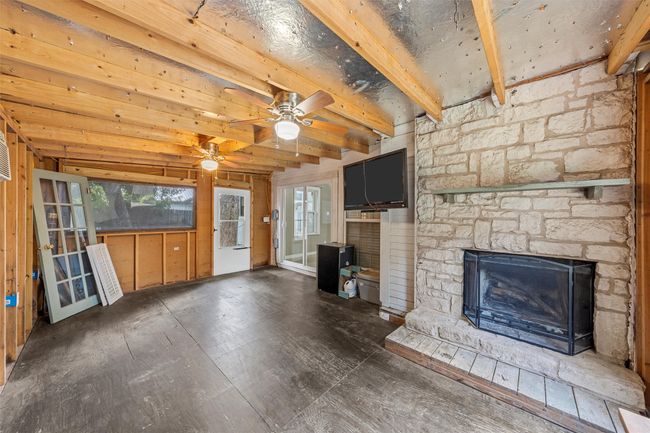 Unfurnished living room with a fireplace, beamed ceiling, wood finished floors, and ceiling fan | Image 24