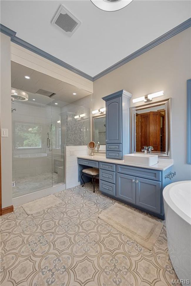 Full bath featuring a stall shower, vanity, a freestanding bath, ornamental molding, and tile patterned floors | Image 25