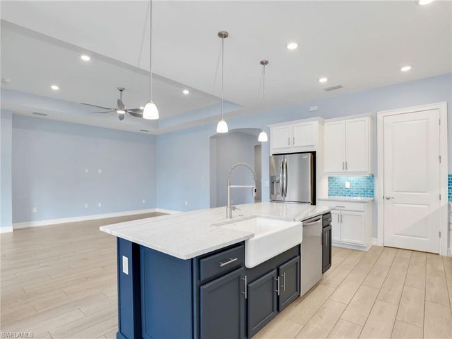 Kitchen featuring sink, decorative light fixtures, a center island with sink, white cabinets, and appliances with stainless steel finishes | Image 15
