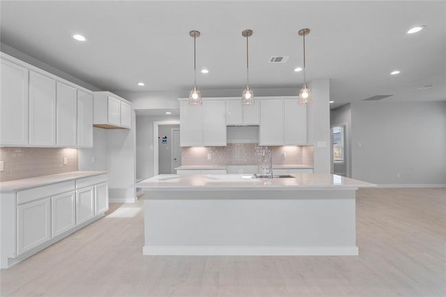 Another gorgeous view of this spacious kitchen featuring the large kitchen island with pedant lighting. The extended quartz countertop allows for a breakfast bar, plenty of space to gather around the kitchen! | Image 7