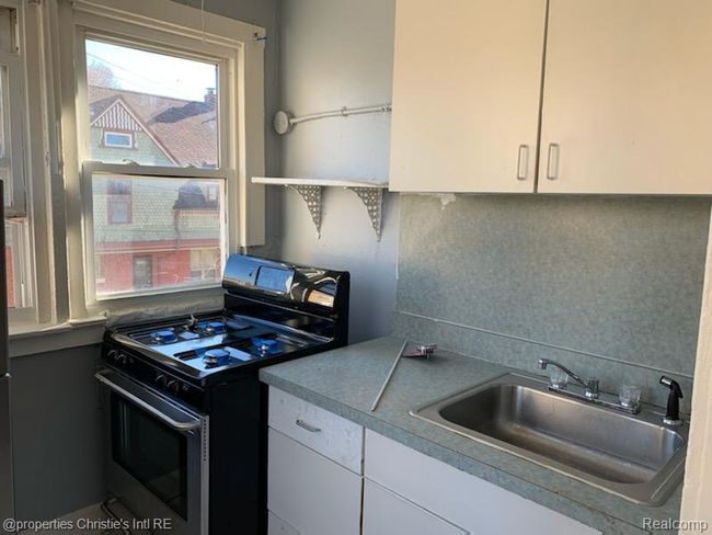 Kitchen featuring range with gas stovetop, open shelves, white cabinets, and decorative backsplash | Image 4