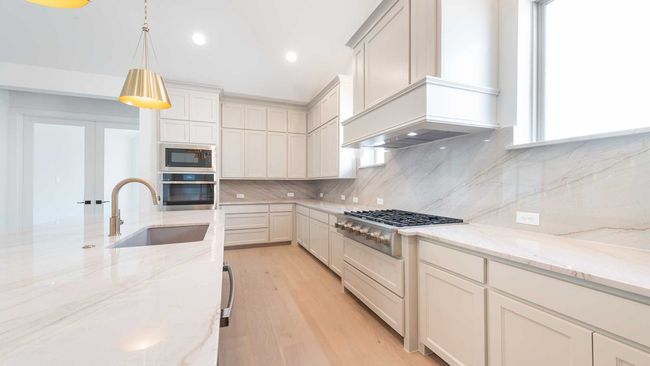 Kitchen with a sink, appliances with stainless steel finishes, light wood finished floors, custom exhaust hood, and backsplash | Image 13
