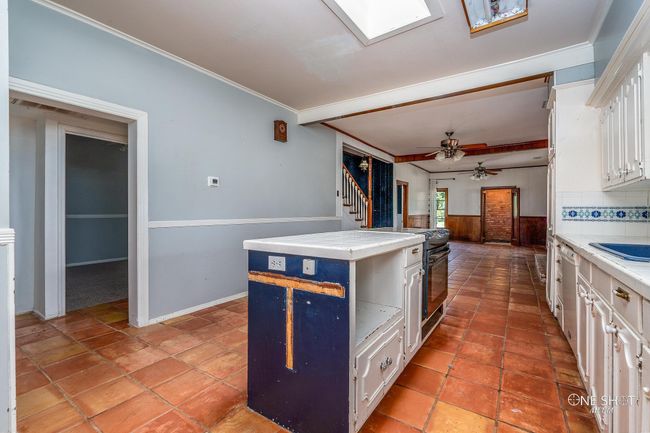 Kitchen featuring white cabinetry, tasteful backsplash, a kitchen island, ceiling fan, and ornamental molding | Image 13