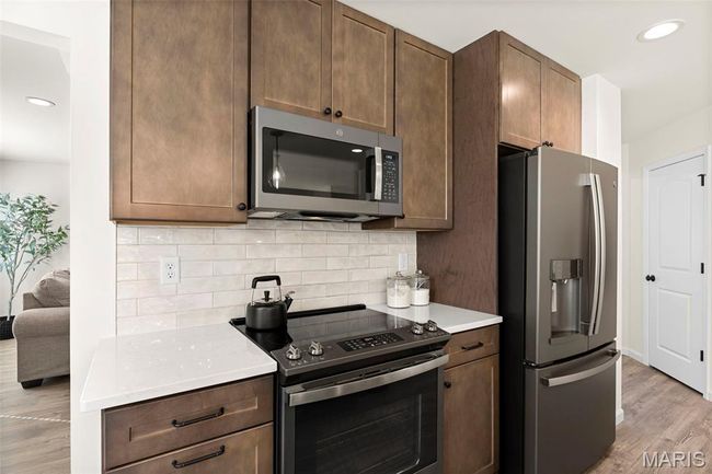 Kitchen featuring appliances with stainless steel finishes, decorative backsplash, light wood-style floors, light countertops, and recessed lighting | Image 12
