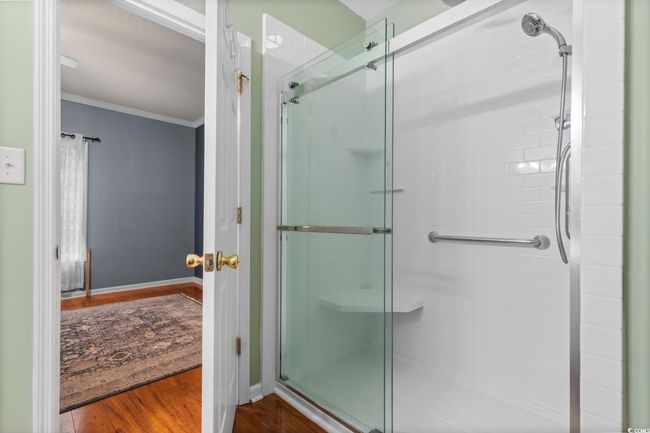 Full bath featuring crown molding, a stall shower, wood finished floors, and baseboards | Image 28