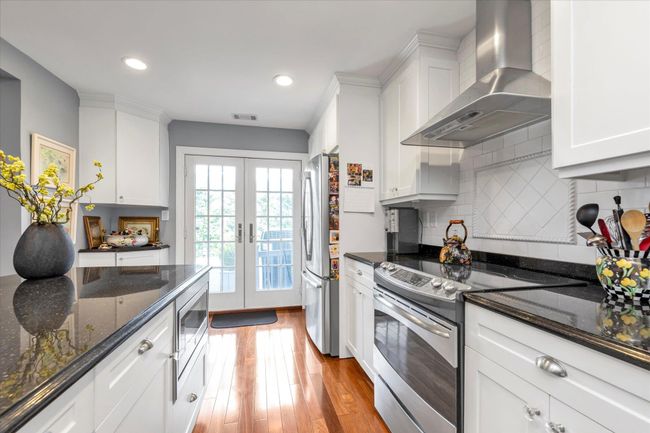Kitchen with wall chimney range hood, visible vents, appliances with stainless steel finishes, french doors, and light wood finished floors | Image 7