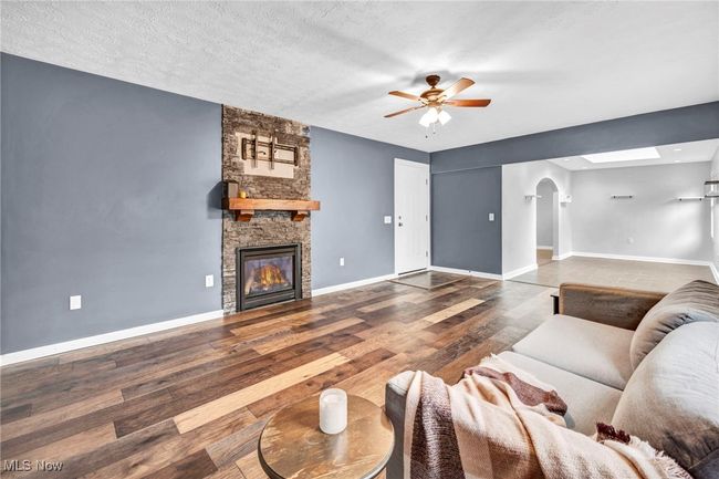 Living room featuring ceiling fan, wood finished floors, and a stone surround on a gas fireplace | Image 18