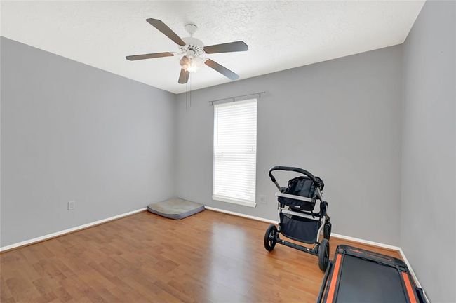 Spacious bedroom featuring natural light, elegant flooring, and a ceiling fan for comfort. | Image 13