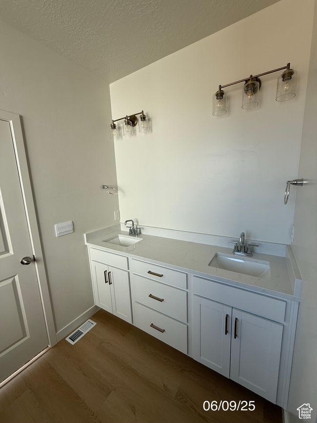 Bathroom featuring wood finished floors, double vanity, and a textured ceiling | Image 7