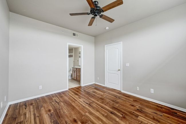 Unfurnished bedroom featuring wood finished floors, ensuite bathroom, and a ceiling fan | Image 18