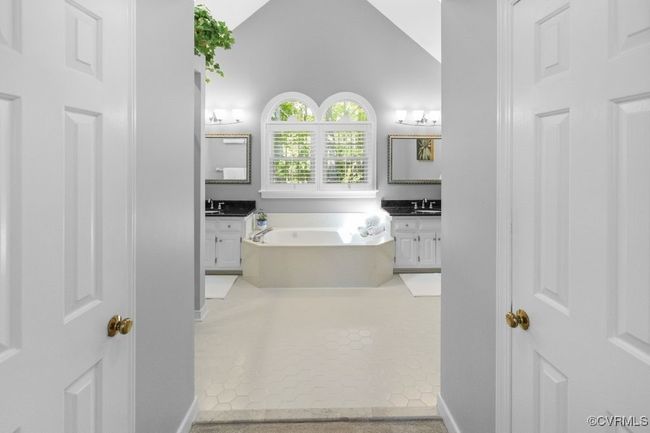 Bathroom featuring a garden tub, vanity, baseboards, tile patterned floors, and vaulted ceiling | Image 26