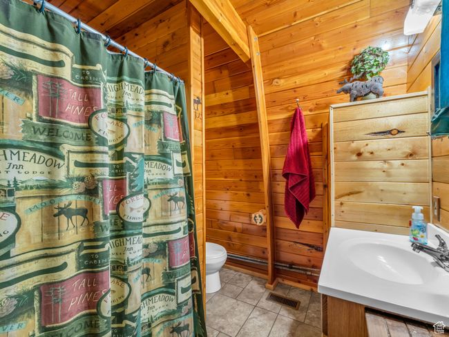 Full bathroom with wooden walls, vanity, tile patterned flooring, curtained shower, and wooden ceiling | Image 15