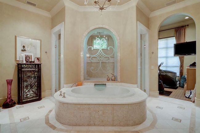 Primary bathroom has large, jetted tub with waterfall filler, large walk-in shower with double shower heads, inlayed marble mosaic walls and porcelain floors, two water closets, utility room, exercise room, Quartzite counters and onyx sinks. | Image 22