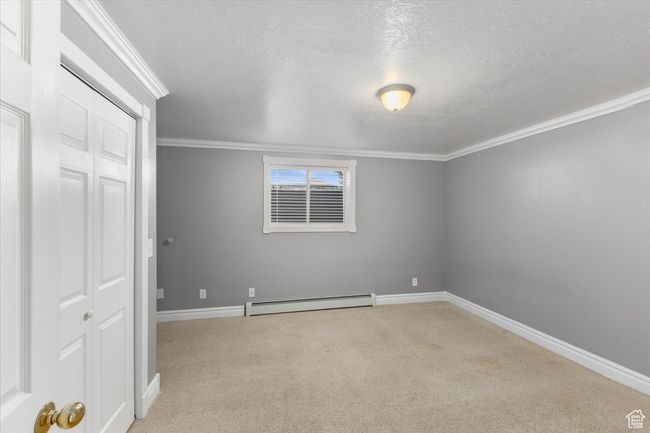 Unfurnished bedroom featuring a closet, baseboards, ornamental molding, carpet flooring, and a baseboard heating unit | Image 19
