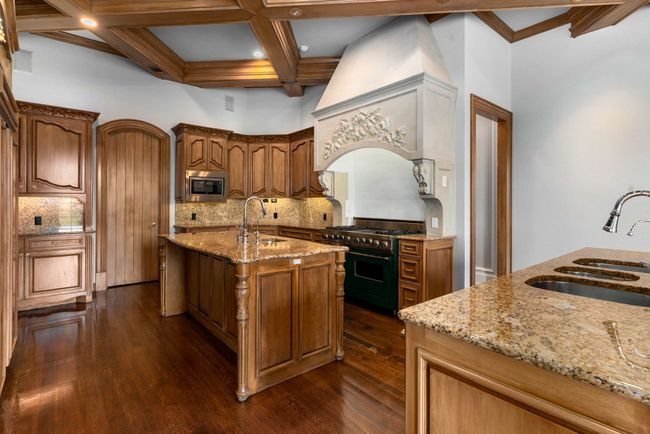 Kitchen featuring appliances with stainless steel finishes, decorative backsplash, light stone counters, dark wood-style flooring, and beam ceiling | Image 20